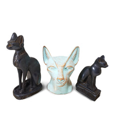 A set of three Egyptian-themed cat statues, with one larger black statue, one smaller black statue, and one patina-colored bust.