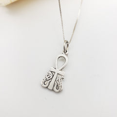 Silver necklace with an ankh and cobra pendant on a light gray background