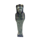 Decorative Egyptian Sehkmet figure on top, leaning against books in a room with plants and wooden paneling.