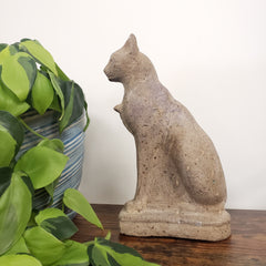 Stone cat sculpture on a wooden post with green leaves in the foreground