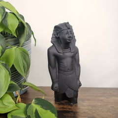 Decorative black sculpture of Ramses with a headrest against a neutral wall.