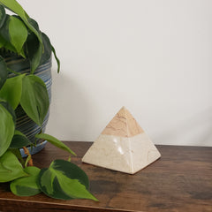 marble pyramid art piece on a wooden surface with green plants.