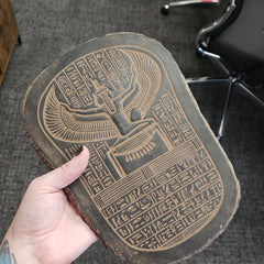 Hand holding a wooden block with hieroglyphics and an Egyptianiform figure.