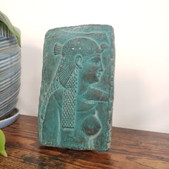 Decorative Cleopatra wall hanging on a white surface and wooden background