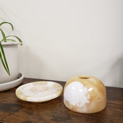 alabaster votive holder a wooden surface with a plant in the background