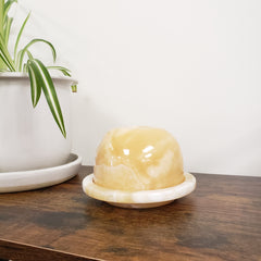 Round alabaster votive holder on a wooden surface with a white background