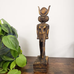 Decorative statue of the Egyptian god Babi with green leaves in the foreground