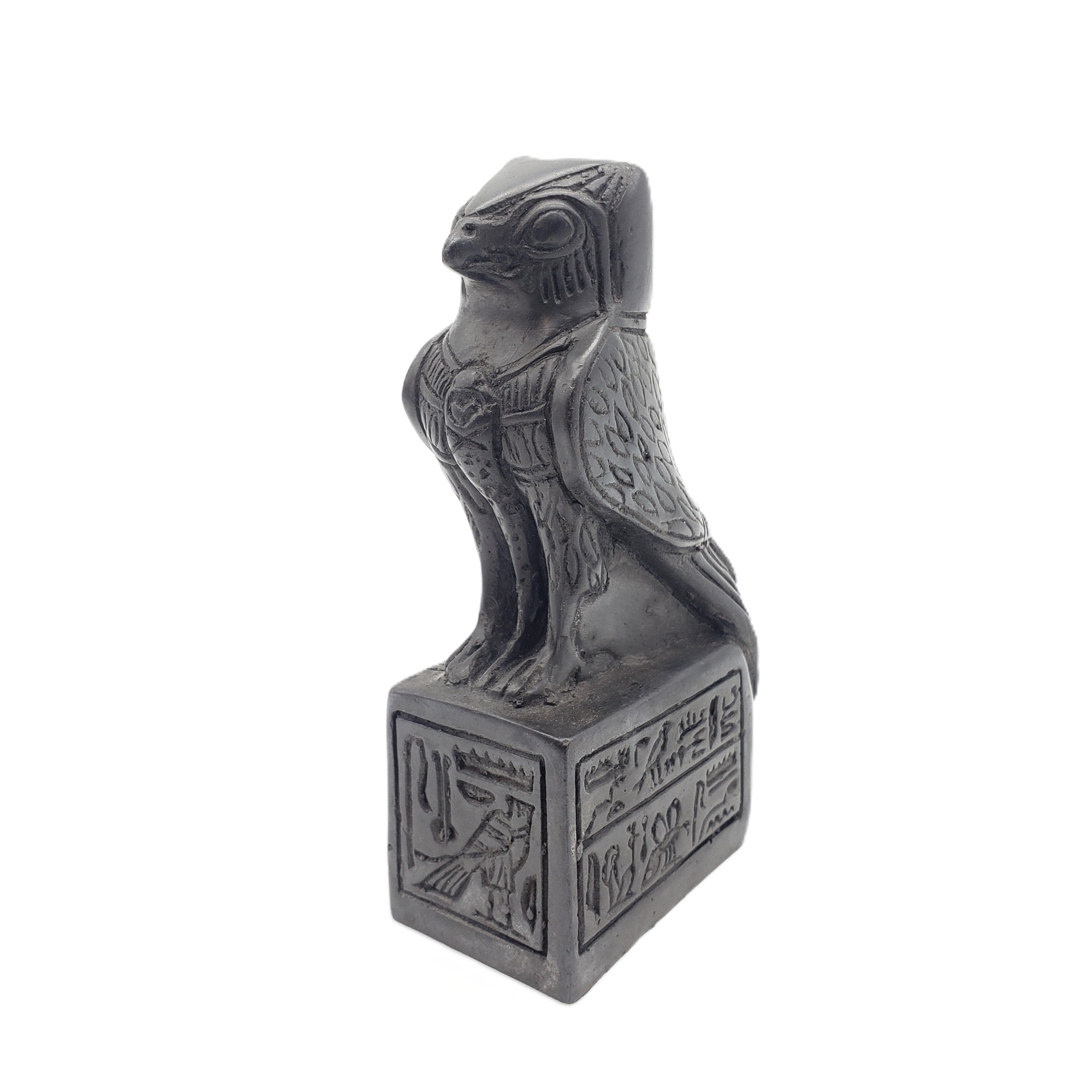 Decorative statue of a falcon on a pedestal with hieroglyphics against a white background