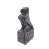 Decorative statue of a falcon on a pedestal with hieroglyphics against a white background