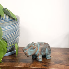 Decorative hippo statue on a wooden door with plants in the foreground.