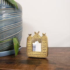 Decorative mirror with Arabic text with intricate designs on a wooden surface.