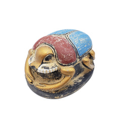 Decorative object resembling a scarab beetle with a colorful shell on a white background