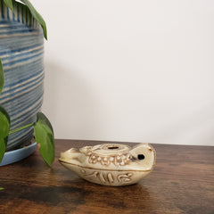 Decorative Egyptian goddess Hathor Oil Lamp on a wooden door with plants in the foreground
