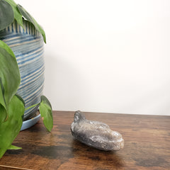 Decorative stone Egyptian goddess Hathor Oil Lamp on a wooden surface with a plant and striped fabric in the background