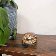 Decorative Egyptian scarab statue on a wooden surface, surrounded by green leaves.