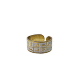 Gold and silver cuff ring with geometric designs on a white background