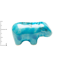 Turquoise-colored ceramic hippo figurine with a ruler for scale on a white background