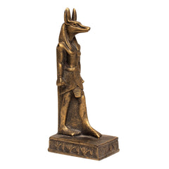 An Egyptian Anubis figurine with a golden-brown metallic finish, standing on a rectangular base against a plain white background.