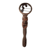 A carved wooden decorative object with a lion head handle and a circular top featuring hanging dark metal discs, shown on a plain white background.