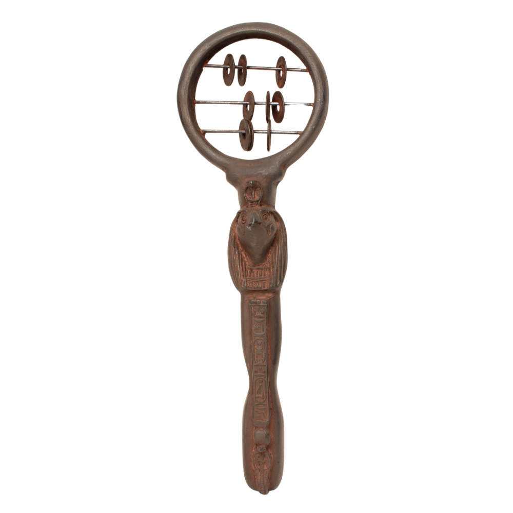 An Egyptian sistrum rattle with a circular frame and a long handle carved with a Ra figure, set against a plain white background.