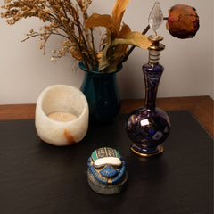Decorative items including a candle, vase with dried flowers, and decorative bottles on a dark surface.