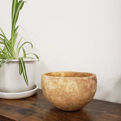 Brown ceramic bowl on a white surface with a wooden edge