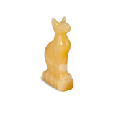 A yellowish marble statue of the Egyptian goddess Bastet, a cat with a human-like figure, sitting on a base.