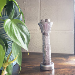 Decorative metal handle on a wooden cabinet with a plant in the foreground
