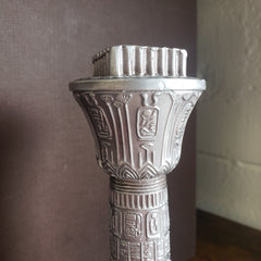 Decorative silver object with intricate designs on a dark surface