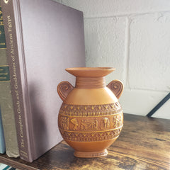 Decorative vase with intricate patterns on a stack of books