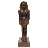 An ancient Egyptian pharaoh statue in a dark finish, standing on a rectangular base with hieroglyphic details, isolated on a white background.