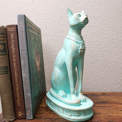 Turquoise Egyptian-style sculpture on a stack of books with a plain wall background