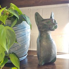 Decorative Patina statue of a cat on a wall with plants in the foreground