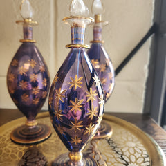 Decorative glass bottle with gold star patterns on a reflective surface