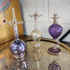 Decorative glass bottles with purple and gold accents on a textured surface.