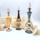Three ornate glass bottles with decorative designs on a white surface.