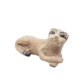 Clay sculpture of a seated figure with animal features on a white background