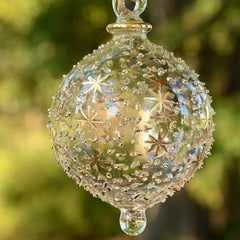 Decorative glass ornament with star patterns against a blurred green background