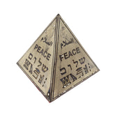 Pyramidal object with 'PEACE' written in multiple languages on a white background