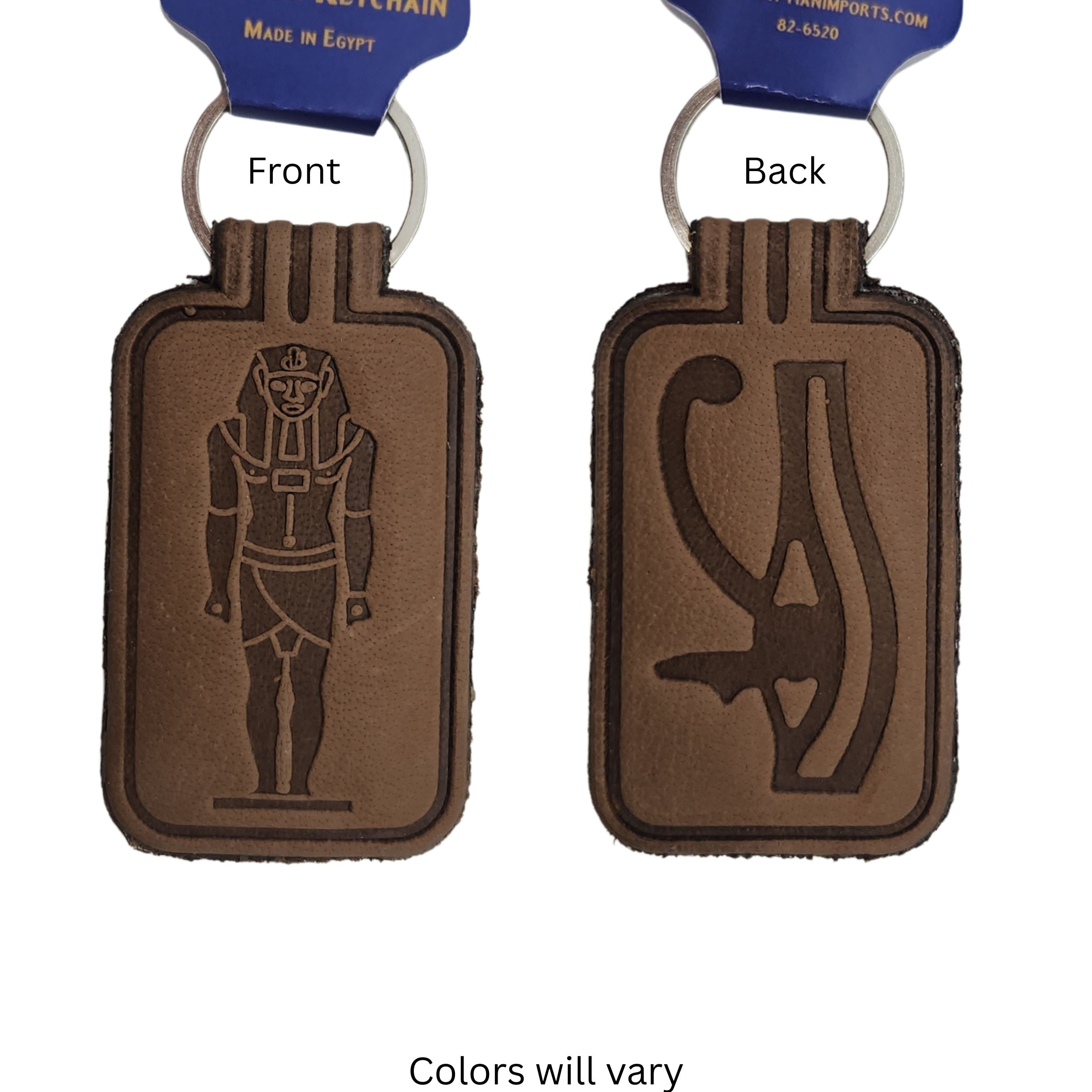 One brown leather keychains shown Front and Back, each attached to a blue hang tag. The front side features an engraved Egyptian pharaoh figure, and the back side features a Eye of Horas symbol.