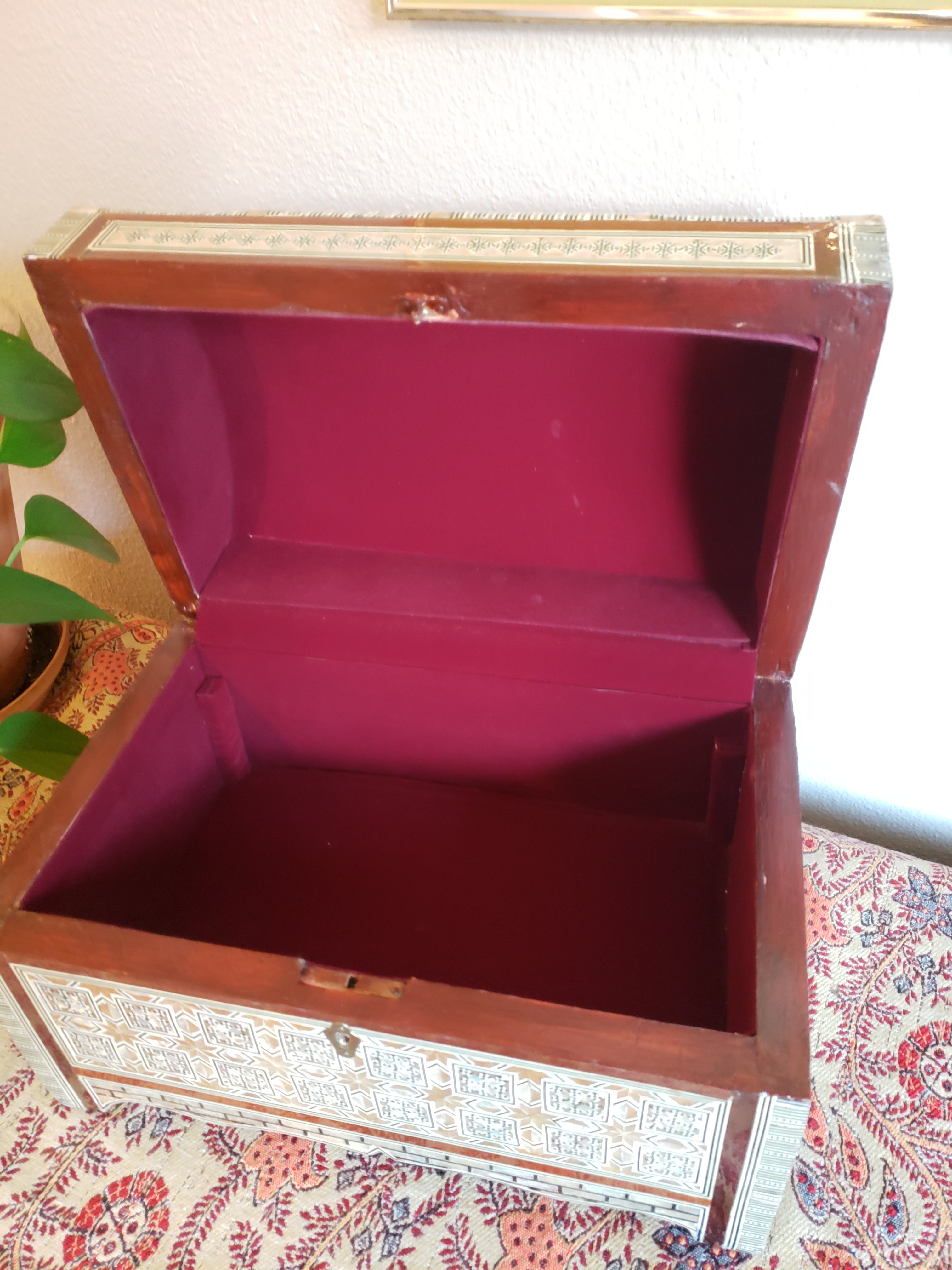 Wooden jewelry box with pink interior on a patterned fabric background