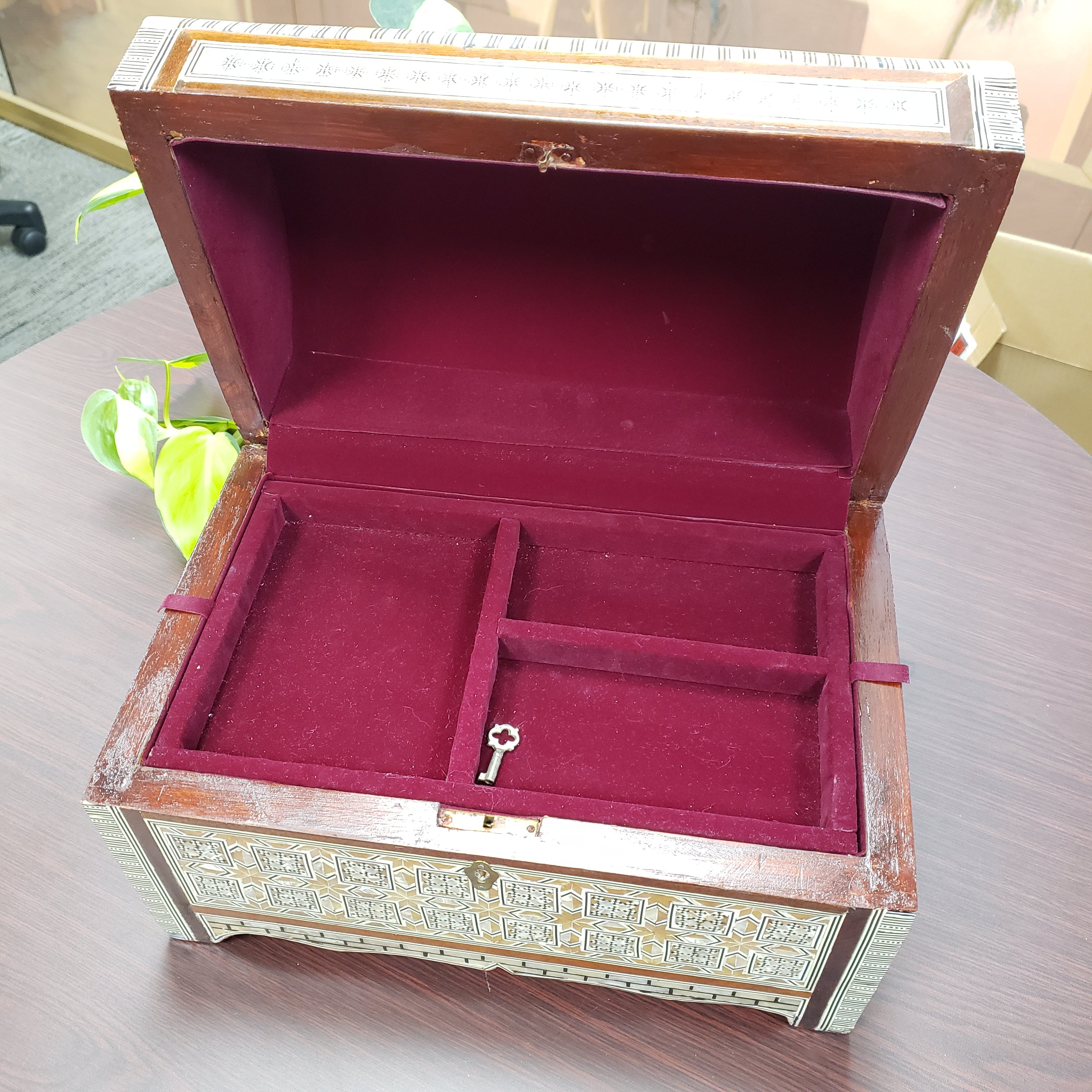 Wooden jewelry box with red interior and decorative patterns on a light background
