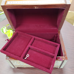 Open jewelry box with maroon interior and key-shaped object on a wooden surface.