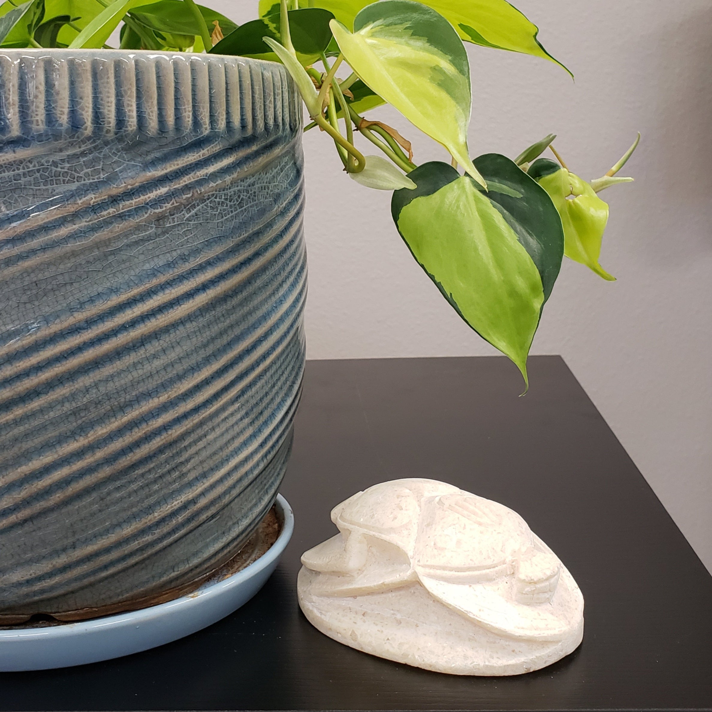 Ceramic pot with a plant and decorative light fixture on a neutral background