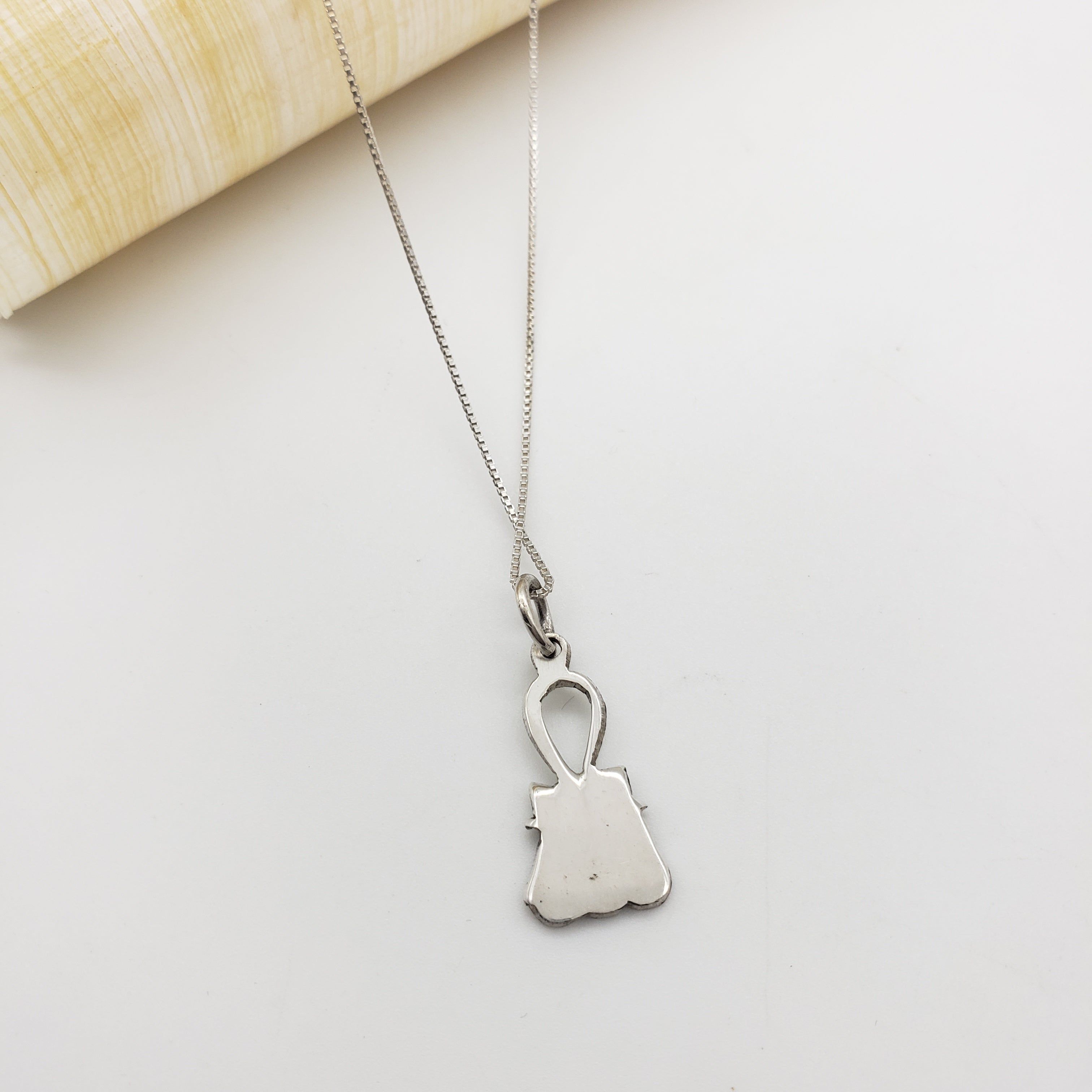 Silver necklace with an ankh and cobra pendant on a light gray background
