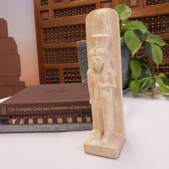 Decorative shelf with a carved wooden figure on top, next to books on a white surface.