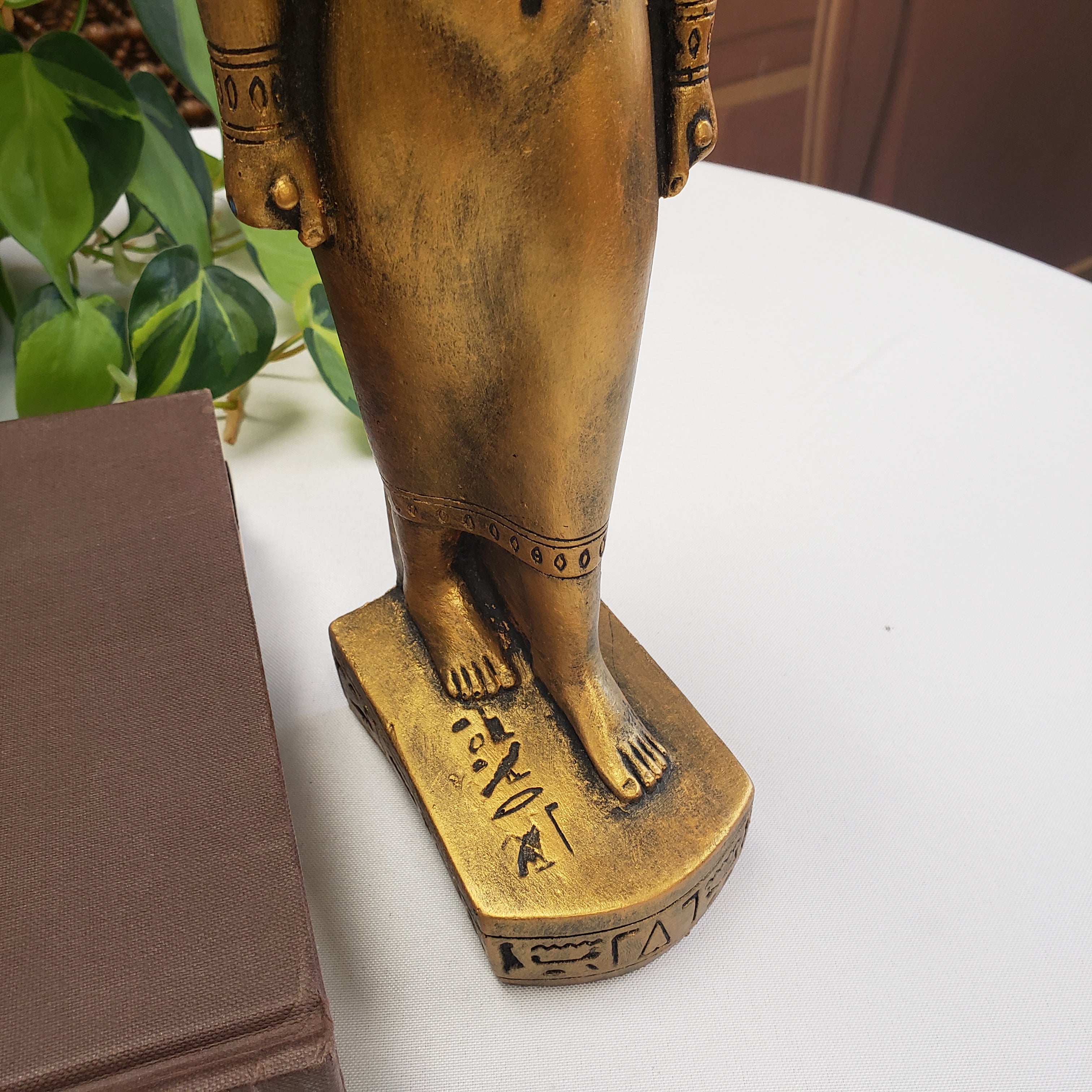 Bronze statue of a seated figure with intricate details on a white surface.