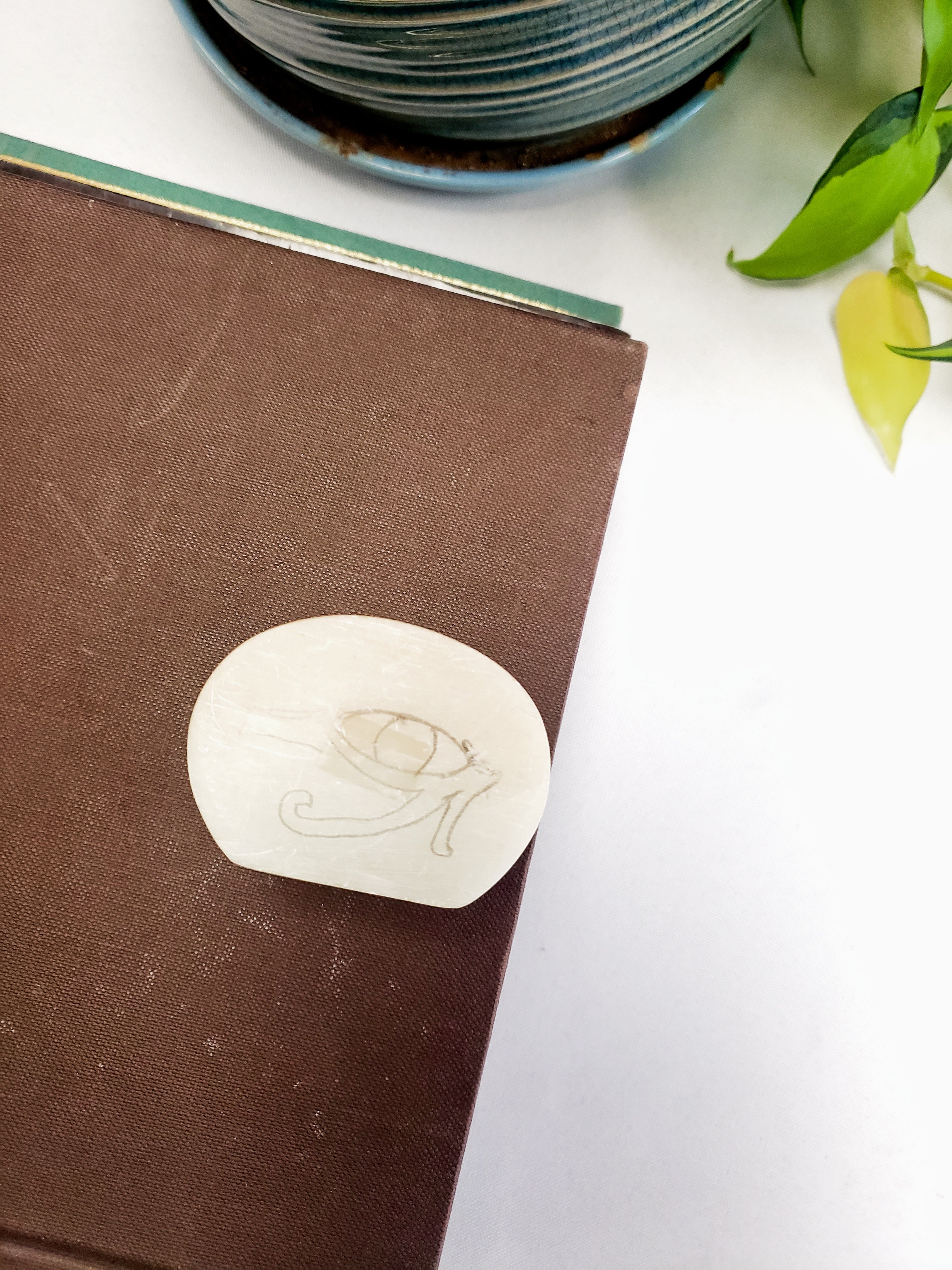 Brown notebook with a white stone featuring a engraved design on a light surface.