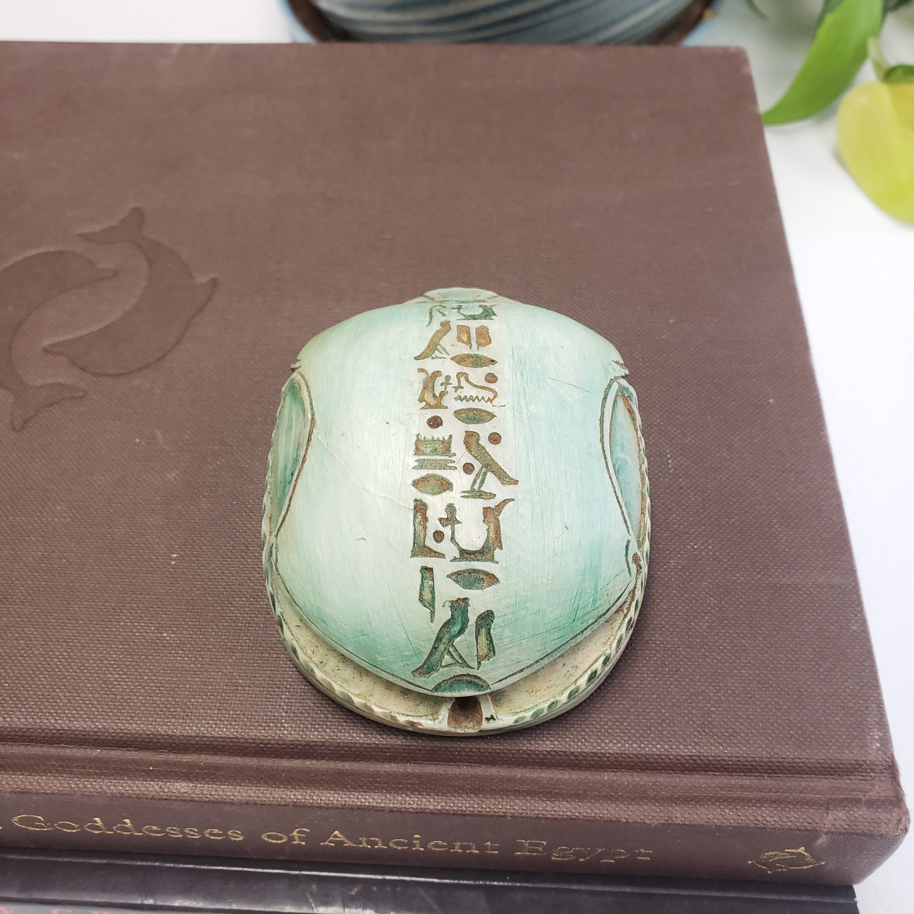 Decorative book with a green scarab object on top