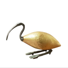 Gold leaf Ibis statue on a wooden surface with a white wall background